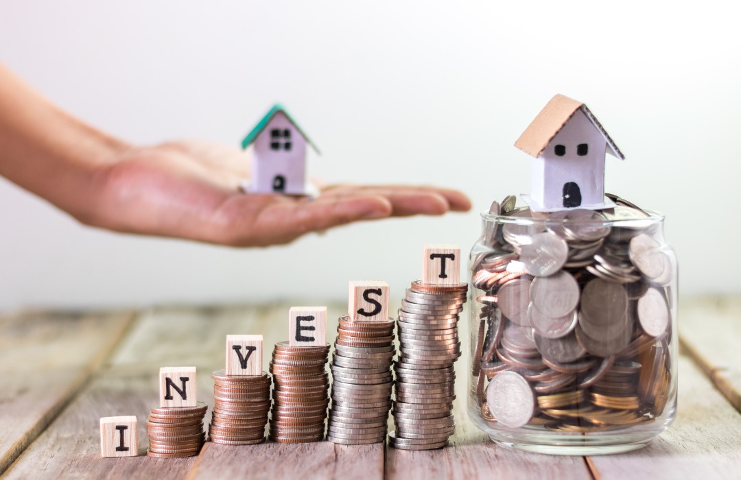 Stacked coins spelling “invest” with house models, representing property investment, wealth building, and financial planning with Innovest advisers in New Zealand.