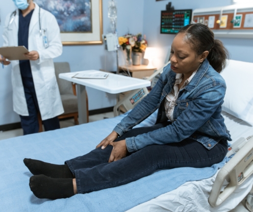 Woman experiencing leg pain during a medical consultation, representing health insurance, income protection, and financial security support from Innovest advisers in New Zealand.