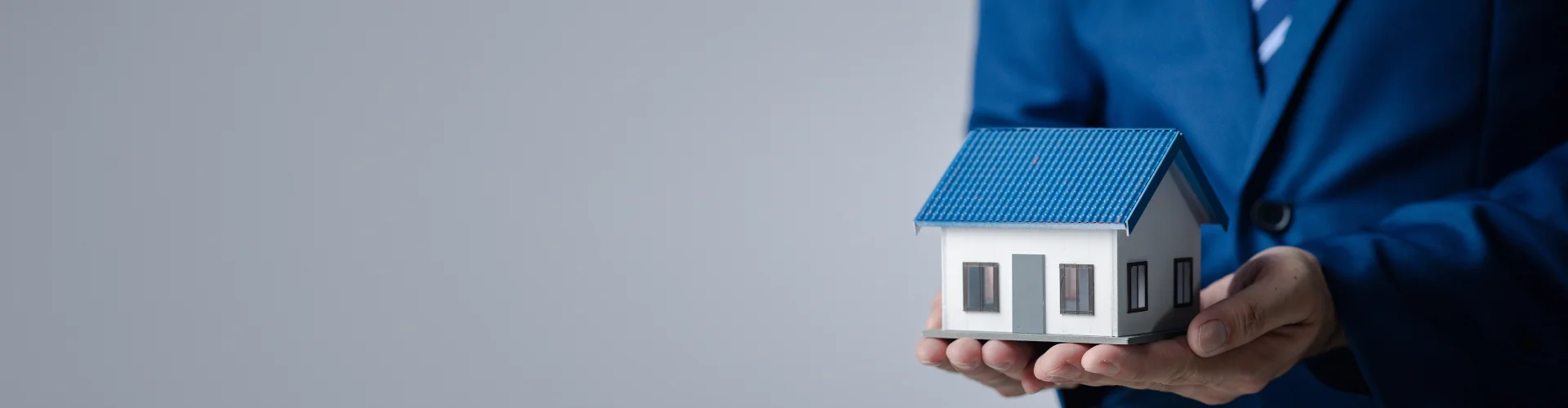 Financial adviser holding a model house, representing home loan guidance, property financing, and mortgage advice with Innovest experts in New Zealand.