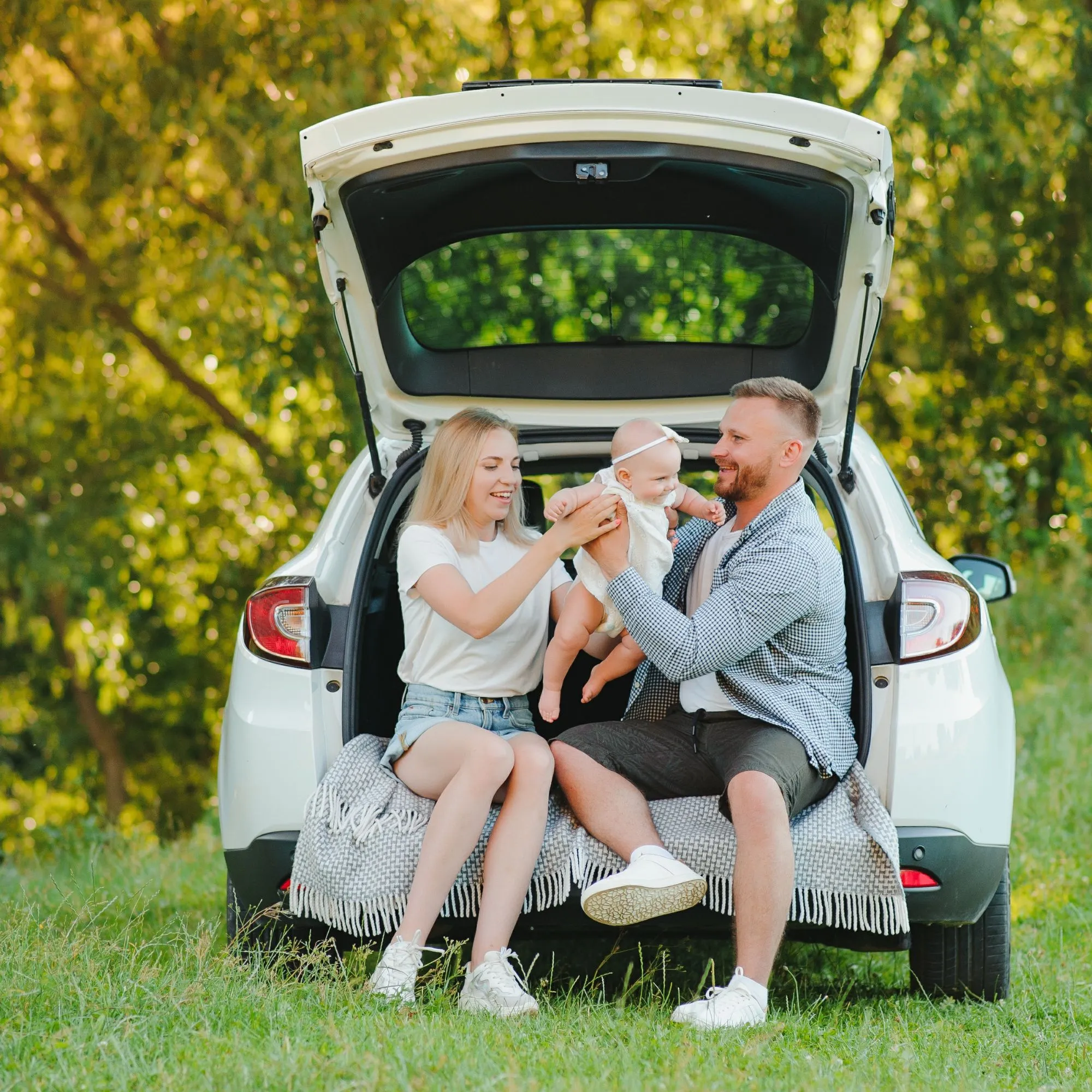 Young family with baby sitting in car boot outdoors, representing financial security, life planning, and a comfortable lifestyle with Innovest advisers in New Zealand.